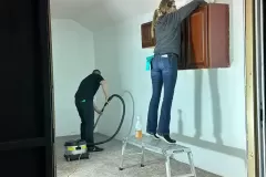 Property restoration students wiping down outer cabinets and sweeping floors